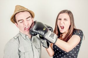 A girl in boxing gloves punching a man, symbolizing aggressive evangelism—an example of how not to share the gospel.